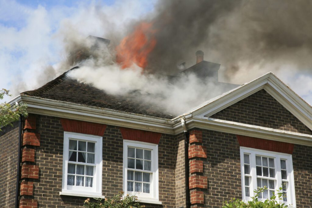 A fire burning on the roof of a house.