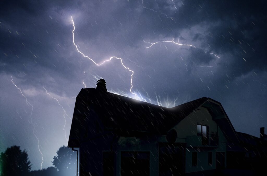 A house with a roof and two lightning bolts in the sky.