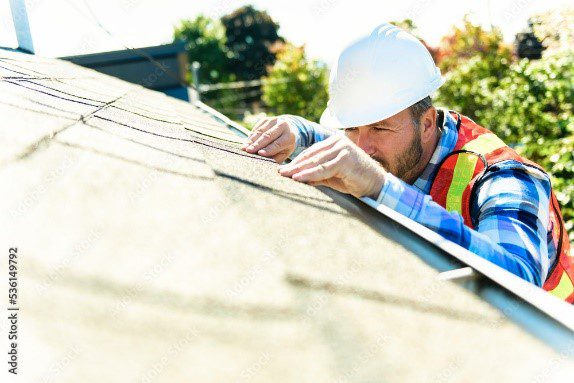 A man in hard hat working on the roof of a house.