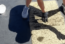 A person wearing black gloves and walking on the sidewalk.